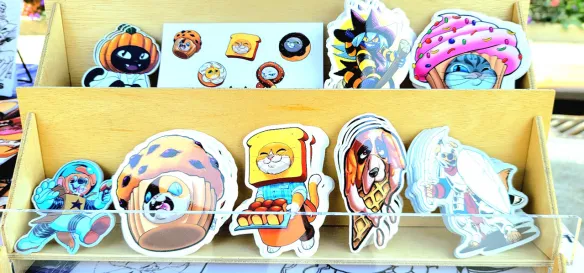 Photograph of Mastafran's table at Alley Art Fest 2026 in Aurora,IL. This picture showcases his selection of stickers.