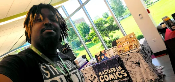 Ryan Self Portrait "Mastafran" Francis at his table at Minicon 2026